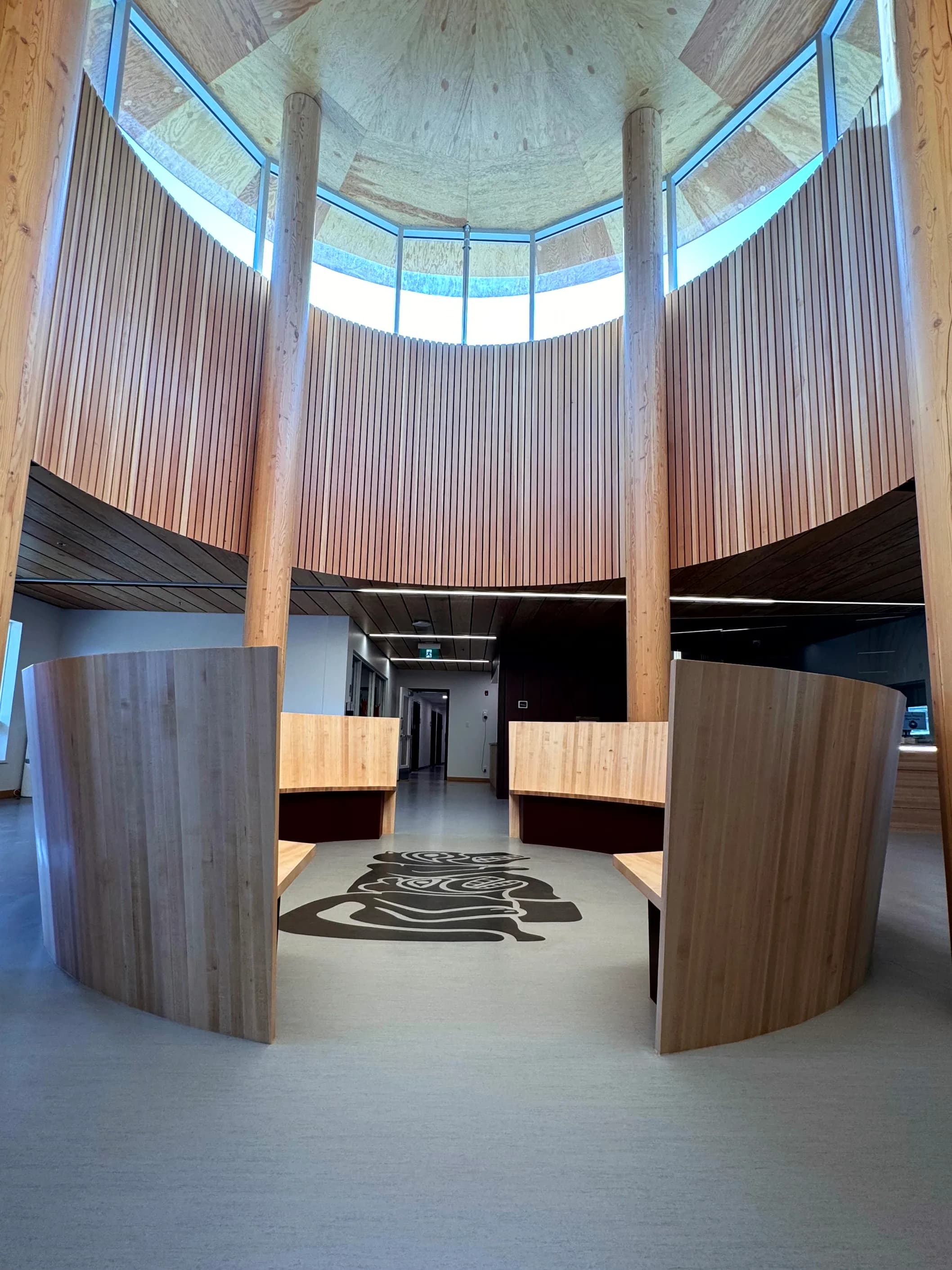 The round gathering space at the heart of the centre, lined with vertical timber and centred on a floor graphic.