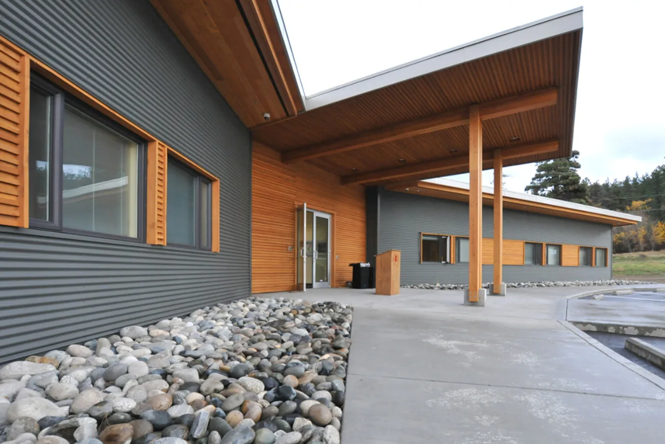 The entrance courtyard, with timber columns, a deep canopy and a bed of river rock.